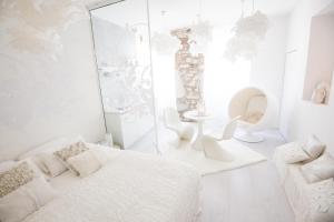 Cette chambre blanche comprend un lit et une chaise. dans l'établissement "Un Lieu Unique" le Gold et le Cocon, à Annecy
