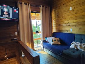a living room with a blue couch and a television at Cabanas LUPE Pedro in Governador Celso Ramos