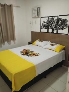 a bedroom with a bed with a yellow and white blanket at Condomínio São Francisco in Petrolina