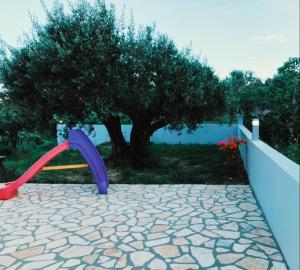 a playground with a purple slide in front of a tree at Olivo Apartment - Studio in Lixouri