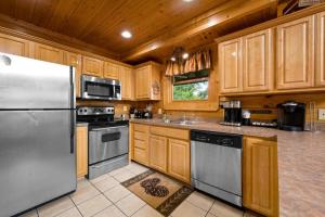 a kitchen with wooden cabinets and a stainless steel refrigerator at Mountain Sunrise by Avada Properties in Sevierville +37 photos