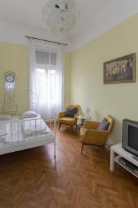 un soggiorno con letto, sedie e TV di Historic Rooms near Gozsdu Udvar a Budapest
