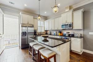 a kitchen with white cabinets and a large island with bar stools at Price Street Place in Savannah