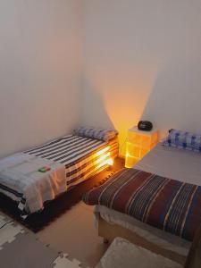 een slaapkamer met 2 bedden en een lampje aan de muur bij hospedagem familiar in Porto Alegre