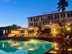 a hotel with a pool in front of a building at Hotel des Mimosas in Juan-les-Pins