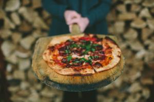 a person holding a pizza on a cutting board at The Market Lofts in Dundee