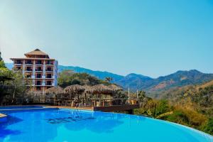 a hotel with a large swimming pool with mountains in the background at River Park Hotel in Puerto Vallarta