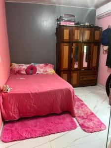 ein Schlafzimmer mit einem rosa Bett und einer Kommode in der Unterkunft Casa na ilha do combu in Acará