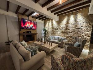 Una sala de estar con sofás y un televisor en una pared de piedra. en MONTEVERDI De LUXURY, en Villa de Leyva