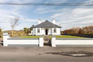 a white house with a fence in front of it at Lime Tree Cottage Foxford County Mayo in Mayo