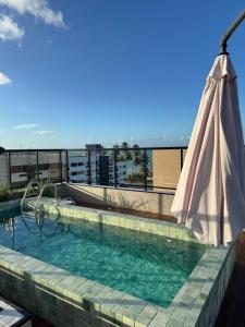 a pool with an umbrella on top of a building at Áurea Flat Cabo Branco in João Pessoa