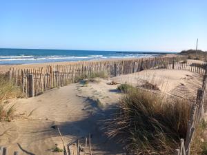 a wooden fence on a beach next to the ocean at Le CENTAURE Proche Centre Naturiste in Cap d'Agde
