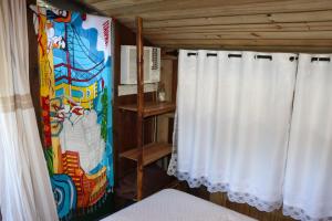 a room with curtains and a painting on the wall at Chalé cabana da mata in Bombinhas