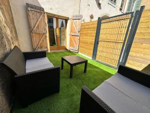 eine Terrasse mit Stühlen, einem Tisch und einem Zaun in der Unterkunft Le Nid en Rotin Apartment in Montbéliard