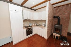 a kitchen with white cabinets and a brick wall at Vikendica Tarzini dvori - privatnost na 2000m2 in Tomislavgrad +18 photos