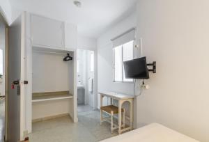 a white room with a desk and a tv on a wall at Hostal Altamar in Almuñécar