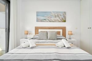 a white bedroom with a large bed with two lamps at Un Sueño Realidad En Torrox in Los Llanos