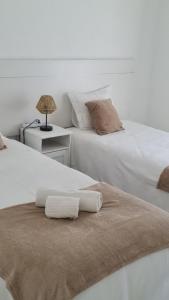 two beds sitting next to each other with towels on them at Apartamento Alagoinha by Umbral in Vila Nova de Milfontes