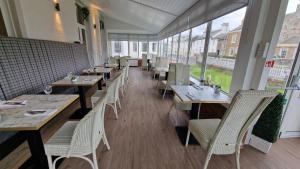a restaurant with wooden tables and chairs and windows at South Beach Hotel in Troon