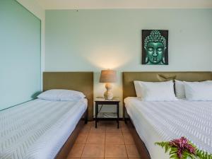 Dos camas en una habitación con un cabezal en la pared. en Vista Ballena, en Uvita