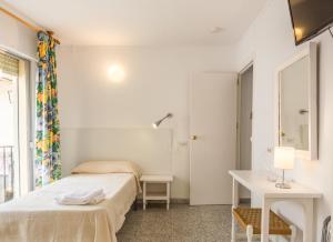 a bedroom with two beds and a table and a mirror at Hostal Altamar in Almuñécar