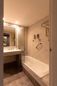 a bathroom with a shower and a tub and a sink at San Miguel Plaza Hotel All Inclusive in Villa San Miguel