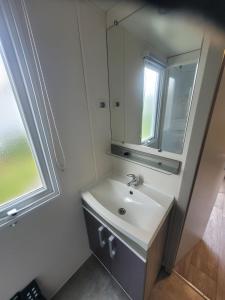 une salle de bains avec un lavabo et un miroir dans l'établissement mobil home, à Lit-et-Mixe