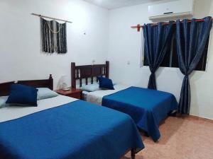 a bedroom with two beds with blue sheets and a window at Casa Itzae in Valladolid +28 photos
