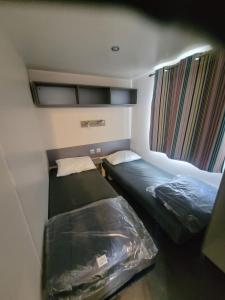 une petite chambre avec deux lits dans une caravane dans l'établissement mobil home, à Lit-et-Mixe