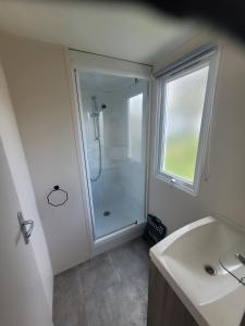 une salle de bain avec une douche et un lavabo et une fenêtre dans l'établissement mobil home, à Lit-et-Mixe