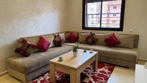 een woonkamer met een bruine bank en rode kussens bij Magnifique appartement Marrakech in Marrakesh