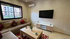 een woonkamer met een bank en een flatscreen-tv bij Magnifique appartement Marrakech in Marrakesh
