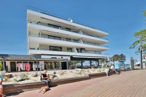 a person sitting on a bench with a dog in front of a building at Haus Stranddistel Stranddistel Appartement 2 in Scharbeutz