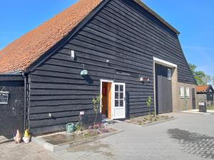 KlundertDe Keet op een boerencamping的一座黑色的大建筑,设有白色的门