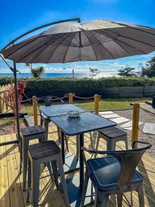 a wooden table and chairs under an umbrella at Ty Baradoz, Maison vue mer et plage à pied in Névez
