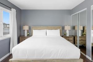 una camera da letto con un grande letto bianco e due finestre di Topside Newport Rooftop Balcony Ocean Views Walk to Pier Marina Village a Newport Beach