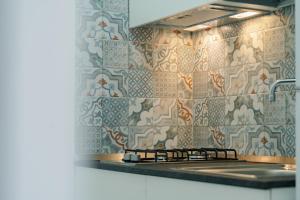 a kitchen with a stove and a tiled wall at La dimora del cavatore in Favignana +134 photos
