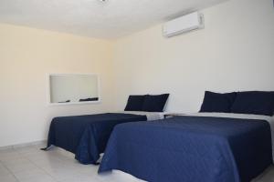 zwei Betten in einem Zimmer mit blauen Laken in der Unterkunft Hotel Esperanza in Esperanza