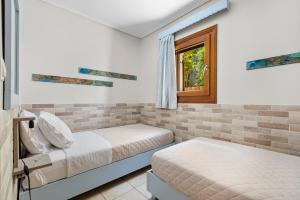 two beds in a room with a window at Spetses Center Comfy Apartment in Spetses