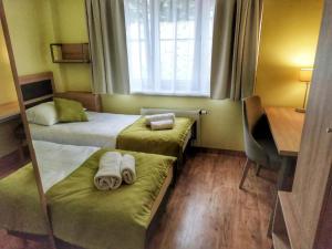 a hotel room with two beds and a desk and a window at Sandacz Otmuchów in Otmuchów