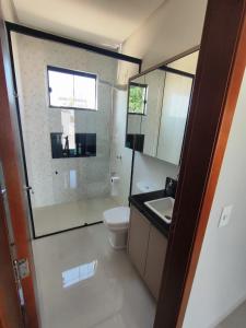 a bathroom with a toilet and a sink and a mirror at Casa para período Bahia Farm Show valor negociável in Luis Eduardo Magalhaes