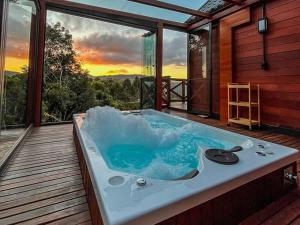 a hot tub on a deck with a view of the sunset at Rancho Texel Chalé de Luxo in Rancho Queimado
