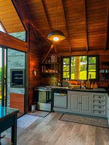a large kitchen with a stove and some windows at Rancho Texel Chalé de Luxo in Rancho Queimado