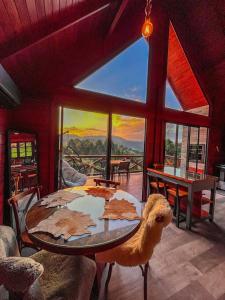 a dining room with a table and a large window at Rancho Texel Chalé de Luxo in Rancho Queimado