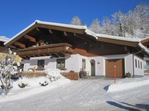 a house with snow on the ground in front of it at Gästehaus Aigner in Saalbach-Hinterglemm