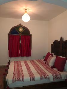 a bedroom with a bed with a red curtain at Dar Zaher in Aourir
