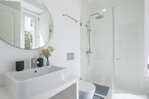 een witte badkamer met een wastafel en een spiegel bij Charming and Cozy beach apartment in Estoril +32 foto's