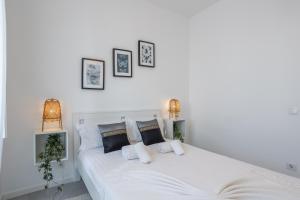 een wit bed met witte kussens en 2 lampen bij Charming and Cozy beach apartment in Estoril