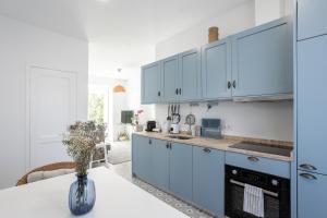 een keuken met blauwe kasten en een witte tafel bij Charming and Cozy beach apartment in Estoril