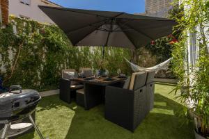 een tafel en stoelen onder een parasol in een tuin bij Charming and Cozy beach apartment in Estoril